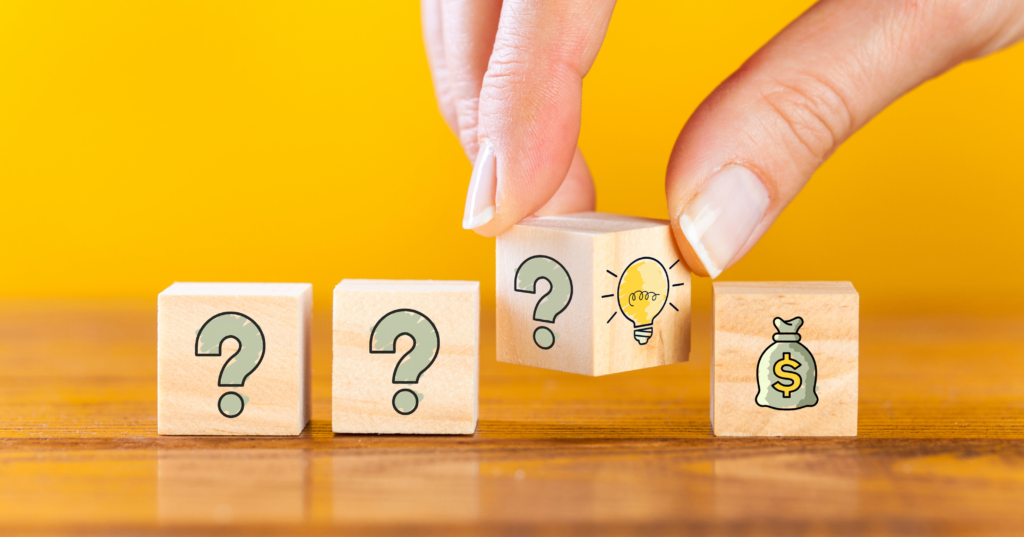 クエスチョンと電球、金袋のアイコン付き木製ブロック。恋とお金の迷いを占いで整理するイメージ
