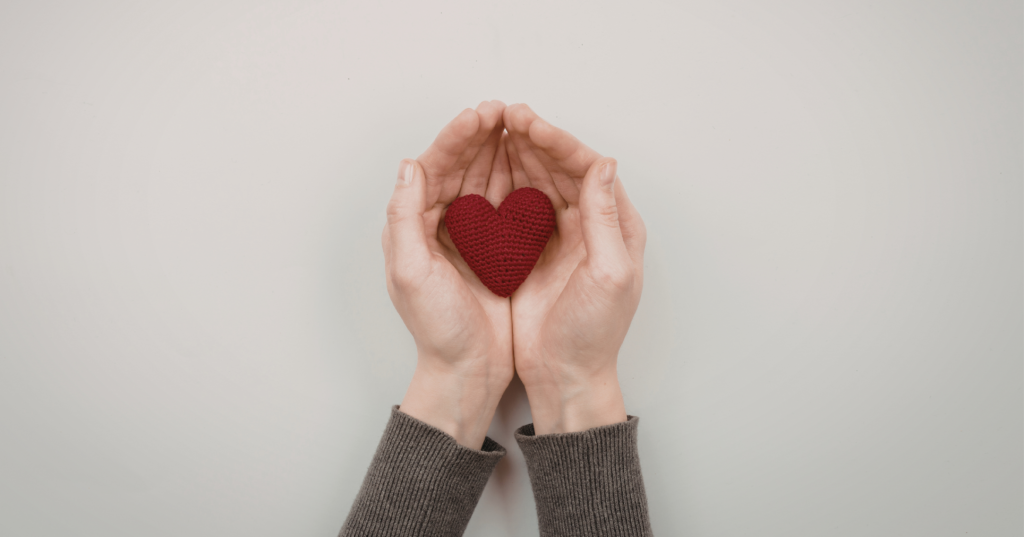 両手で赤いハートを包む写真。恋の気持ちを占いで守りたいイメージ